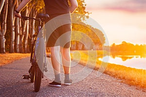 Biker with his bicycle at sunset next to a river ready to ride