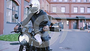 Biker in leather gloves and black hoodie starts motorcycle