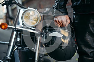 Biker in leather jacket with helmet in hand