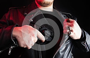 Biker in leather jacket pulling out revolver