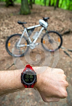 Biker looking on wearable sports watch and mountain bike