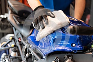 Biker man cleaning motorcycle , Polished and coating wax on fuel tank at garage. motorcycle maintenance and repair concept