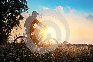 Biker on mountain bike adventure in beautiful flowers nature of summer sunset