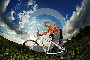 Biker in orange jersey riding on green summer field