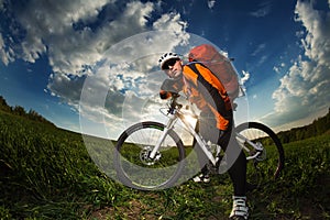 Biker in orange jersey riding on green summer field