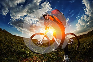 Biker in orange jersey riding on green summer field