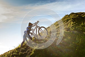 Biker pushes bicycle up in the mountains photo