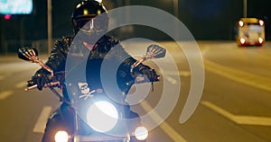 Biker rides Motorcycle slowing down and stopping on crossroads in city at night