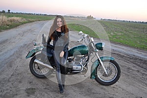 Biker sexy girl sitting on vintage custom motorcycle. Outdoor lifestyle toned portrait