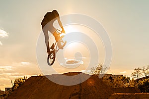 Biker silhouette doing an jump. Man on bmx bike against sunshine sky. High BMX jump.