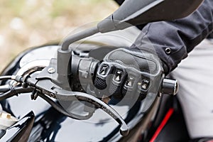 Biker sitting on motorcycle, close-up view on hands on handlebar