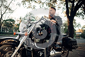 Biker sitting on a motorcycle leaning on a helmet