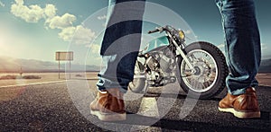 Biker standing near the motorcycle on an empty road