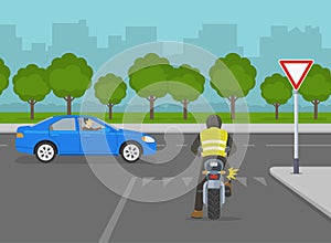 Biker is about to turn right on road with `give way` sign. Yield to traffic on the major road.