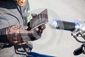 Biker trying to call with cellphone, holding smartphone with hands wearing leather gloves, close up view