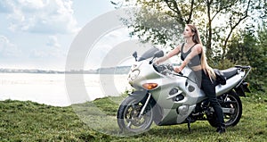 Biker woman with motorcycle rest near a pond