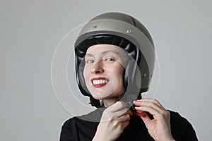 Biker young woman smiling and putting her helmet posing over white background.