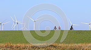 Bikers on a dike and wind turbines