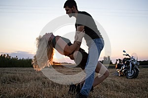 Bikers man and woman stopped at the side of the road to rest and kiss passionately. Photos of loving motorcyclists at sunset. The