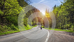 Bikers on mountainous highway, biker on the road in sunset light riding on curve road pass across Alpine mountains, extreme