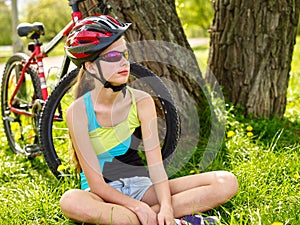 Bikes cycling girl wearing helmet have a rest sitting under tree.