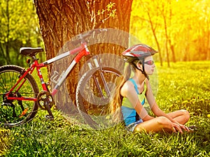 Bikes cycling girl wearing helmet have rest sitting under tree.