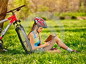 Bikes cycling girl wearing helmet read book rest near bicycle.