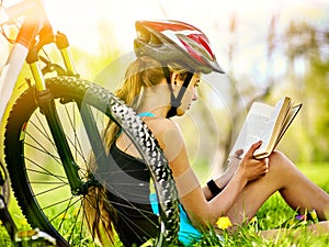 Bikes cycling girl wearing helmet read book on rest near bicycle.
