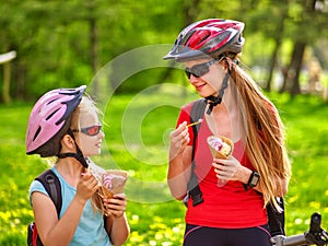 Bikes cycling girls with rucksack cycling eating ice cream cone in summer park.