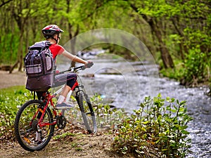 Bikes girl with big rucksack cycling fording throught water .