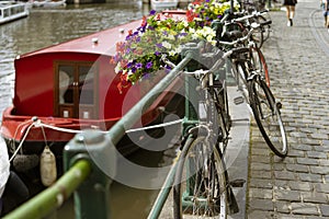 Bikes parked next to a canal and close to a boat, in Belgium. Picturesque scene. Planters with flowers and plants. photo