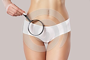 Bikini area female body. Holding a magnifying glass near the pubic base