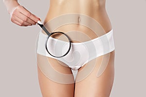 Bikini area female body. Holding a magnifying glass near the pubic base photo