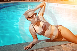 Bikini-clad woman enjoys poolside relaxation. Poolside ambiance. Capturing woman& x27;s relaxed time near pool.