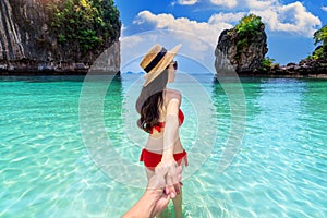 Bikini girl holding man`s hand and leading him to koh hong island in Krabi, Thailand photo