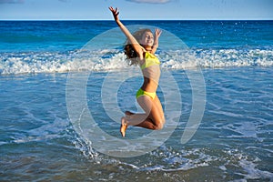 Bikini girl jumping in Caribbean sunset beach