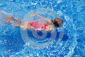 Bikini kid girl swimming on blue tiles pool