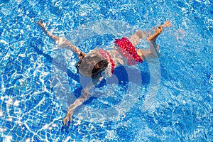 Bikini kid girl swimming on blue tiles pool