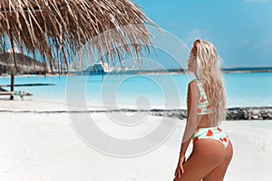 Bikini Model enjoying on tropical beach. Pretty slim girl posing on exotic island in turquoise ocean. Blonde in trendy swimwear
