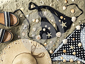 Bikini set, summer shoes and straw hat on beach sand