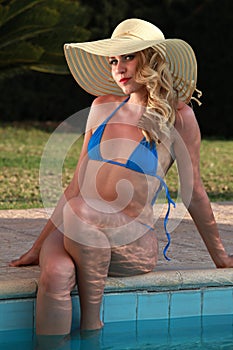 Bikini woman in hat by the pool