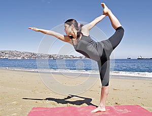 Bikram yoga dandayamana dhanurasana pose at beach photo