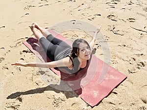 Bikram yoga paorna salabhasana pose at beach