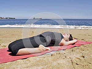 Bikram yoga supta bajrasana pose at beach photo