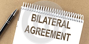 BILATERAL AGREEMENT text on a notepad with pen, business