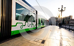 BILBAO, SPAIN-DECEMBER 19, 2021 : Sidewalk with people walking near Euskotren city tram runs on tramway track. Modern transport in