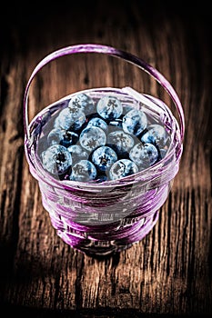 Bilberries in basket on vintage wooden board