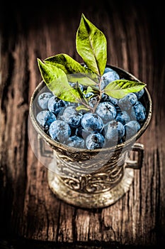 Bilberries in metal bowl on vintage wooden board vertical view