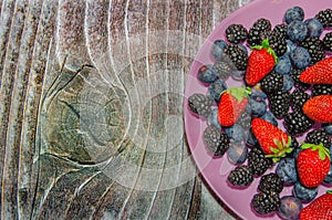 Bilberries and strawberries on a pink plate