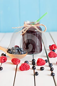 Bilberries in wood spoon. Crimson raspberry and